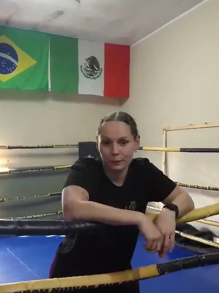 Trenerka Ola w czarnej koszulce klubowej oparta o liny ringu na sali Fitness and Boxing